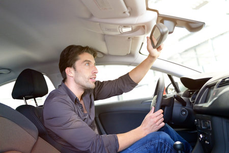 Car dealership - young handsome man sits in a car and  buying a car