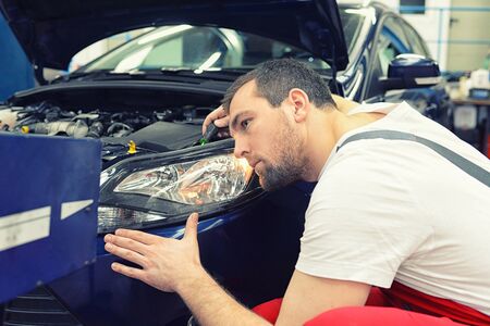 adjusting the headlights on the car by mechanics in a garageの写真素材