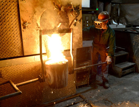 workers in a foundry casting a metal workpiece - safety at work and teamwork 