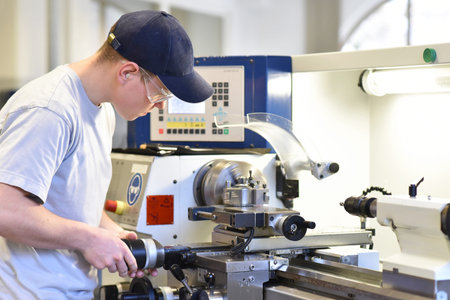 young apprentice in vocational training working on a turning machine in the industry