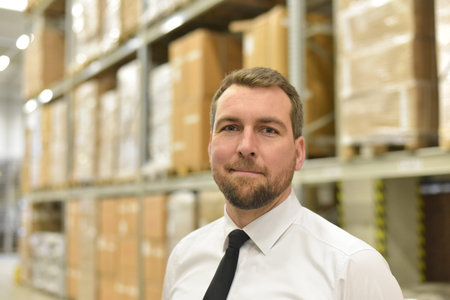 portrait friendly businessman/ manager in suit working in the warehouse of a company