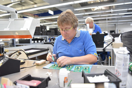 Friendly woman working in a microelectronics manufacturing factory - component assembly and...