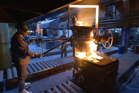 workers in a foundry casting a metal workpiece - safety at work and teamwork