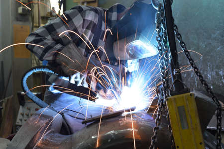 Welder in protective clothing at the workplace in an industrial company in steel construction