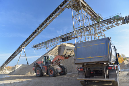 Gravel pit: building and wheel loader loading gravel onto a truck