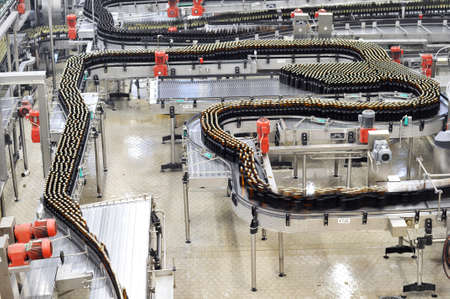 Modern factory in the food industry - beer brewery - conveyor belt with beer bottles and machines for productionの写真素材