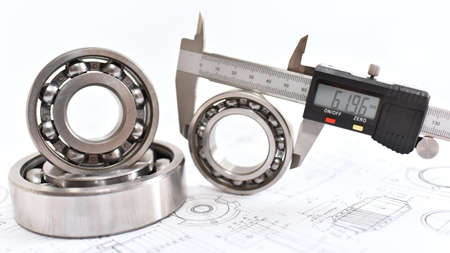 Quality control in modern mechanical engineering - caliper gauges, technical drawing and ball bearings on white backgroundの写真素材