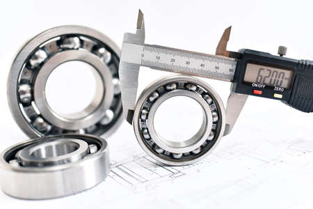 Quality control in modern mechanical engineering - caliper gauges, technical drawing and ball bearings on white backgroundの写真素材