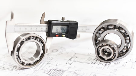 Quality control in modern mechanical engineering - caliper gauges, technical drawing and ball bearings on white backgroundの写真素材