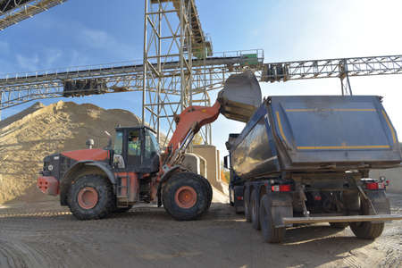 Gravel pit: building and wheel loader loading gravel onto a truckの写真素材