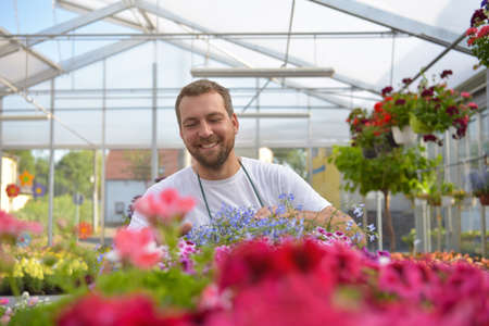 happy worker growing flowers in a greenhouse of a flower shopの写真素材