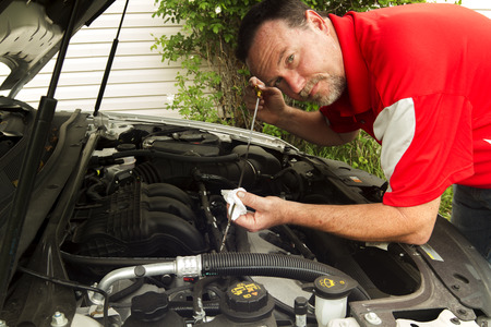 A mechanic checking the oil in a car.の写真素材