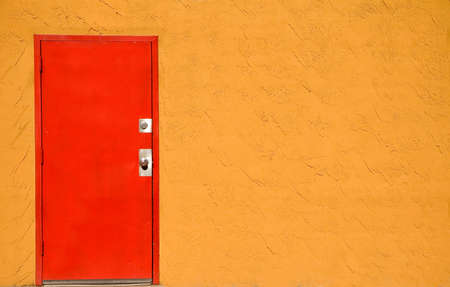 Red steel door in a stucco wall.の写真素材