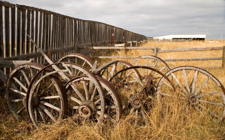 Old wagon wheels against a fence.の写真素材