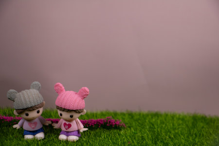Two cute child figurines holding hands on green grass with copy space, expressing friendship, love, innocence, and sweet childhood moments.の写真素材