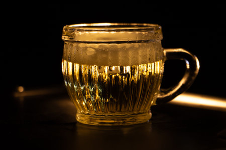 Golden beer in glass mug with condensation on dark background, refreshing drink and bar beverage concept.の写真素材