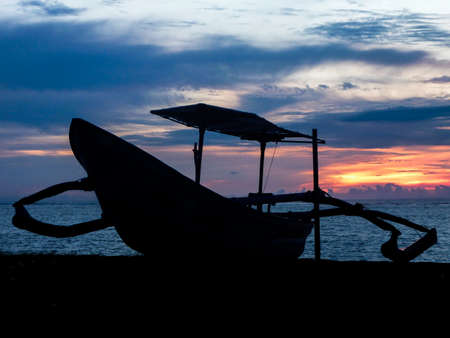 Typical Indonesian boat on a Bali beach at sunset.の写真素材