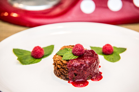 A chocolate cupcake with chocolate frosting served with fresh ripe raspberry.の写真素材