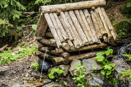 Natural source of spring water in forest flowing from a wooden wellの写真素材