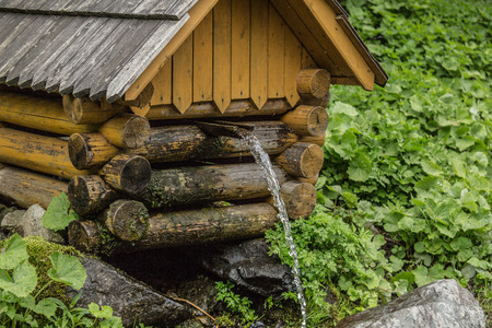 Natural source of spring water in forest flowing from a wooden wellの写真素材