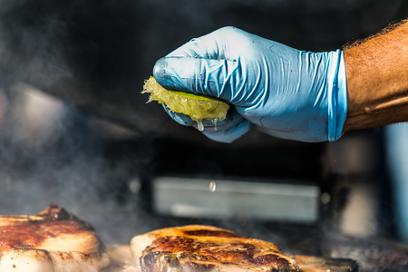 The chef squeezing lemon juice onto grilling steak. Fresh, delicious grilled meatの写真素材