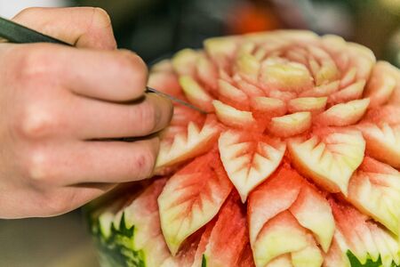 Close up crafts carved watermelon with the hand and carving knife の写真素材