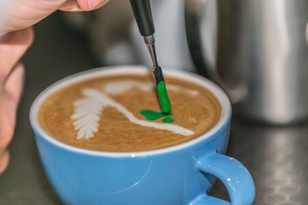 Barista making an art from the fresh milk in the little ceramic cup of the delicious hot espressoの写真素材