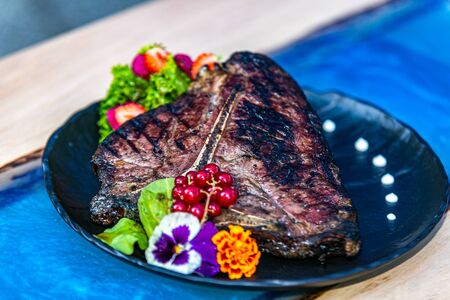 Close up grilled steak with fresh salad on a black plate.Food cooked on grill. Grilled and barbecue conceptの写真素材