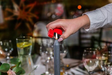 Hand with a lighter lighting a candle on festive dinner table. Close up. Christmas timeの写真素材