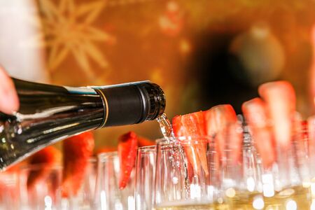 Waiter with a bottle of champagne in his hand fills the glasses.Detail on the pouring champagne into glassの写真素材