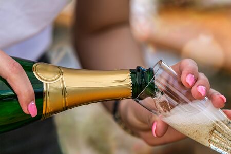Waiter with a bottle of champagne in his hand fills the glasses.Detail on the pouring champagne into glassの写真素材