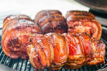 Fresh, delicious grilled porchetta. Grilling porchetta on BBQ. Closeup of a porchetta on a grill, detail on the crunchy skin の写真素材