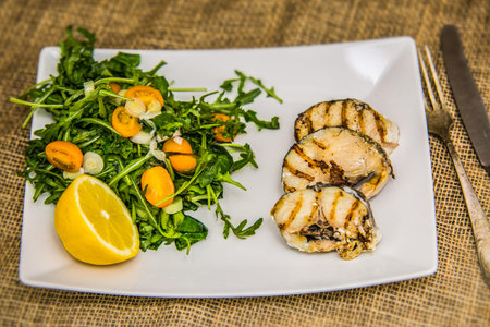 Grilled fish fillet with fresh vegetables served on plate. The food in the restaurant. Food styling...