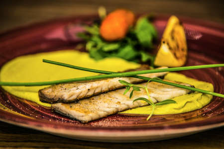 Grilled fish fillet with fresh vegetables served on plate. The food in the restaurant. Food styling and restaurant meal serving.の写真素材