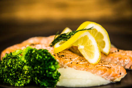 Salmon fillet with lemon and mashed potatoes on plates. The food in the restaurant. Food styling and restaurant meal serving.の写真素材