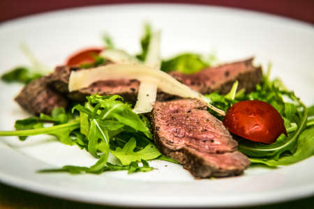 Slices of pork meat with cheese and vegetables on plates. The food in the restaurant. Food styling and restaurant meal serving.の写真素材