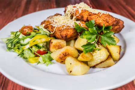 Fried pork schnitzel studded with cheese with potatoes and vegetables. The food in the restaurant. Food styling and restaurant meal serving.の写真素材