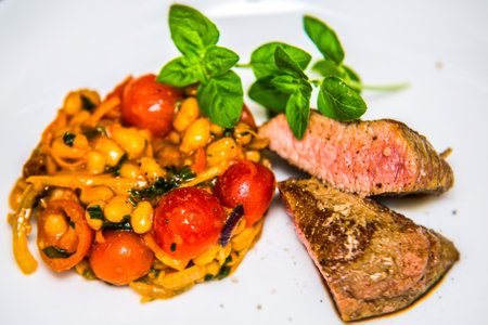 Pork tenderloin steak with bean salad and tomatoes. The food in the restaurant. Food styling and restaurant meal serving.の写真素材