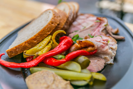 Smoked knee with hot peppers, cucumbers and bread. Food styling and restaurant meal serving.