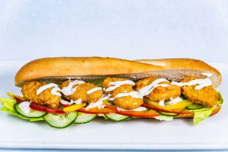 Baguette stuffed with turkey nuggets and vegetables. Food styling for street food. Closeup.の写真素材