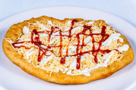 Langos stuffed with grated cheese and dressing.Langos is a traditional hungarian food. Food styling and restaurant meal serving.の写真素材