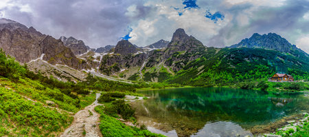 A dramatic landscape shot of a hiking path at the edge of Green Lake (Zelene pleso). Massive granite...