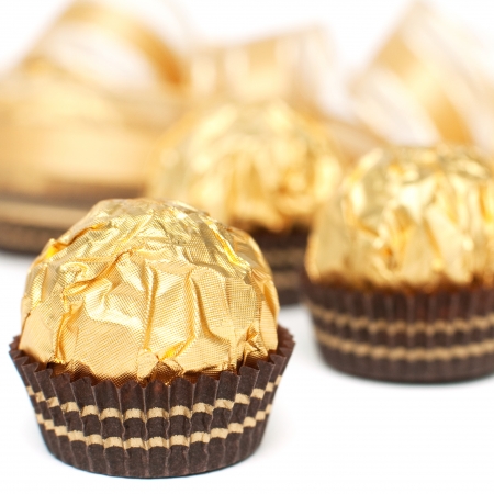 Close up of pralines with gold ribbon in the background isolated on white, square imageの写真素材