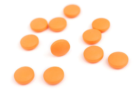 Close up of orange pills isolated on white, shallow depth of field