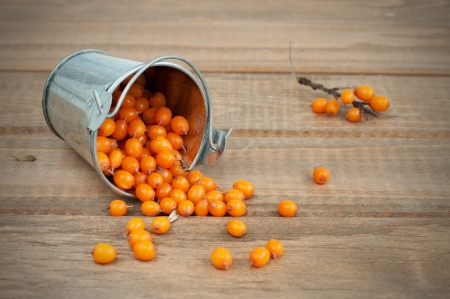 Close up of fresh sea-buckthorn in bucket on wooden table, horizontalの写真素材