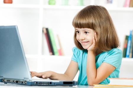 Cute little girl smiling and looking at laptop の写真素材