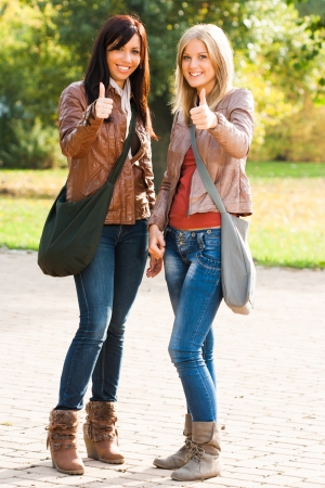 Portrait of two young students showing ok signの写真素材