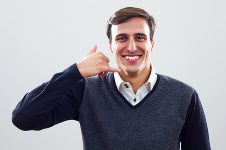 Young businessman showing call me gesture の写真素材