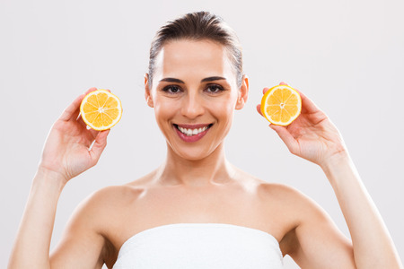 Beautiful woman is holding slices of lemon and looking at camera.の写真素材