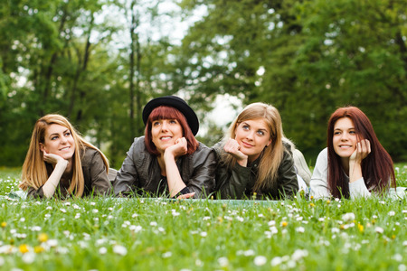 Portrait of four young girls lying down in the park and enjoy in nature.の写真素材
